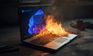 a Windows 11 laptop on a table with a fire coming out of it.